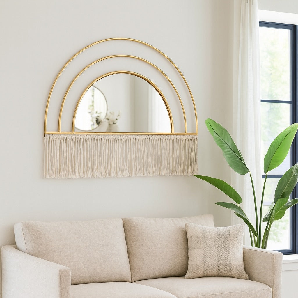 Decorative wall mirror with gold frame and fringe above a beige sofa in a bright room.
