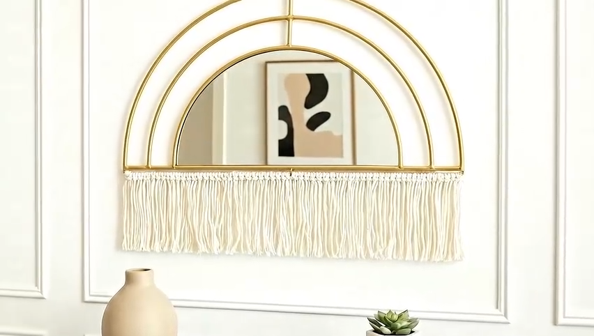 Decorative wall shelf with gold arch and white fringe against a white wall.